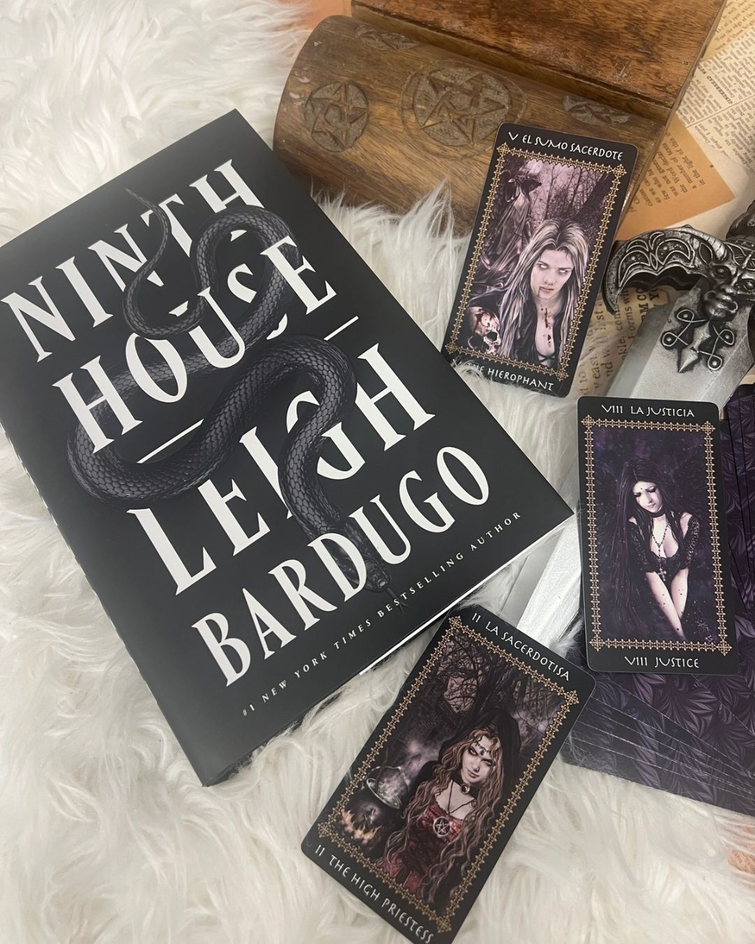 Ninth House by Leigh Bardugo, featuring its black serpent cover alongside Gothic tarot cards, a carved wooden chest and an ornate dagger in a dark academia books display.
